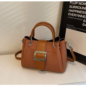 Detailed view of caramel bucket bag featuring textured fabric and large silver buckle