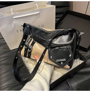 Close-up of contrast leather shoulder bag with polished metallic brand logo plate