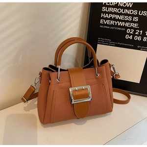 Close-up of caramel brown bucket bag featuring twill texture and silver square buckle