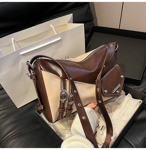 Detail view of brown and beige patchwork underarm bag with metal buckle in gift box