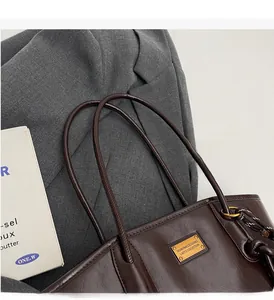 Detailed close-up of chocolate brown tote bag with golden metal logo and slim handles