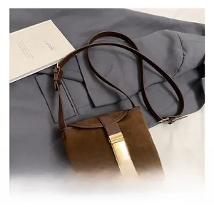 Detail view of vintage brown suede crossbody bag with elegant gold metal buckle closure