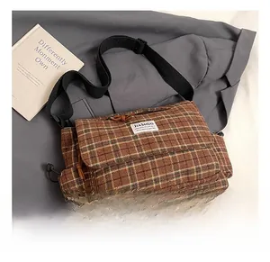 Close-up of brown plaid small square bag with flap design and fabric shoulder strap