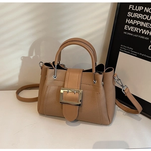 Detailed macro view of the textured brown bucket bag with gold buckle and leather strap