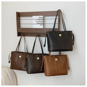 Detail of four colorful leather tote bags with side drawstrings and gold buckles