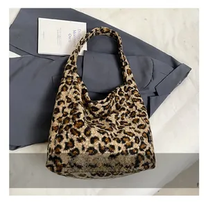 Détail montrant la texture en peluche léopard et la large bandoulière du sac fourre-tout