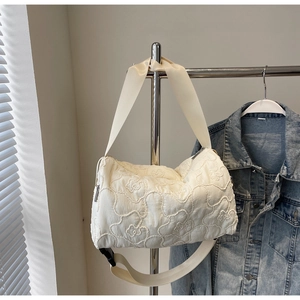 Detail of floral quilted texture on cream canvas shoulder bag with wide strap