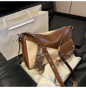 Detail of color-block crossbody bag with buckle straps in a premium gift box
