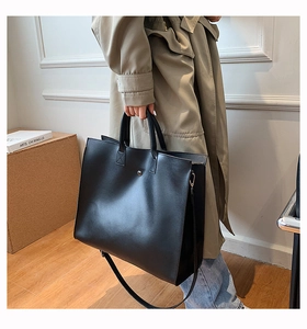 Detailed macro view of minimalist black leather tote bag with elegant silver metal buckle