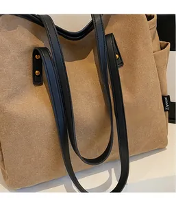 Close-up of khaki canvas tote bag with black leather straps and side pocket details