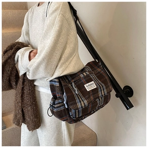Detail view of brown plaid wool texture shoulder bag with drawstring and fabric label