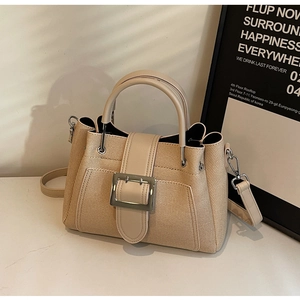 Detail view of the oat-colored woven bucket bag with leather strap and silver buckle