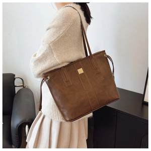 Side view of a vintage dark brown tote bag on a model featuring gold metal accents