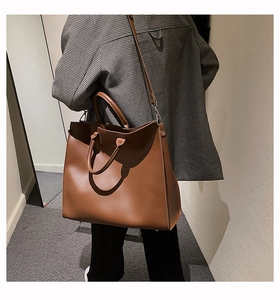 Brown leather tote bag worn by model showing size and adjustable shoulder strap detail