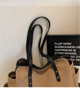 Detail of canvas tote bag with black leather straps and gold rivet accents