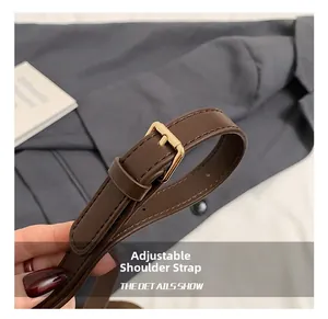 Detail of adjustable dark brown leather shoulder strap with golden metal buckle