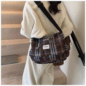 Detail of checkered crossbody bag with adjustable wide strap and branded woven label