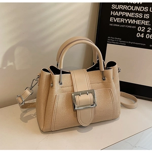 Detail of beige bucket bag featuring twill weave texture and oversized silver buckle
