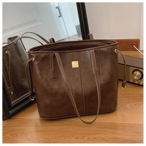 Detail of vintage brown tote bag featuring gold metal plate and drawstring side