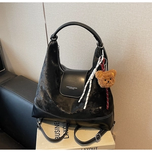 Detail of black Hobo tote bag with textured faux leather and cute brown bear pendant