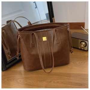 Detail of a brown leather tote bag showing gold hardware and stylish side drawstrings