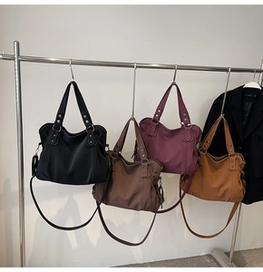 Détail de grands sacs fourre-tout en diverses couleurs avec sangles à rivets et similicuir souple