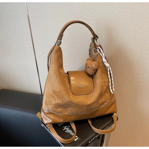 Detail of caramel leather tote bag featuring suede texture and decorative silk scarf