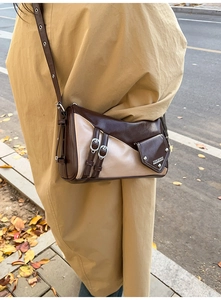 Detail of vintage patchwork crossbody bag with metal buckle and pocket on khaki coat