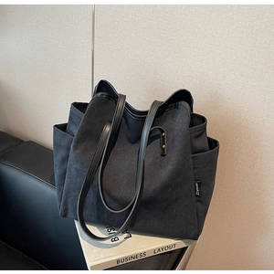 Detail of the high-capacity canvas tote bag featuring black leather trim and metal rivets
