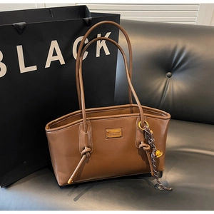 Detail of brown leather tote bag with silk scarf and metallic fashion collection tag