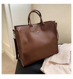 Detailed view of brown leather tote bag with sturdy handles and circular metallic lock