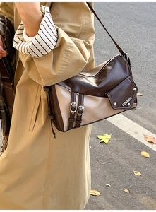 Detail of retro color-block underarm bag with metal rivets and adjustable buckles