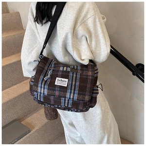 Detail of retro plaid messenger bag showing vintage texture and woven check pattern