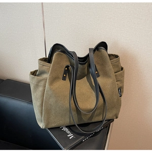 Detail of army green canvas tote bag with black leather handles and side brand tag