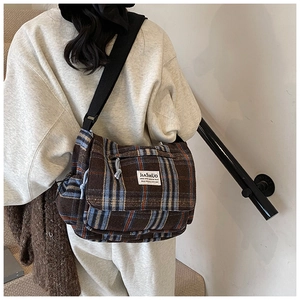 Detail of checkered woolen crossbody bag with wide strap and side drawstring details