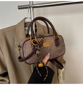 Detail view of a vintage brown boston bag with golden hardware and hand-held close-up