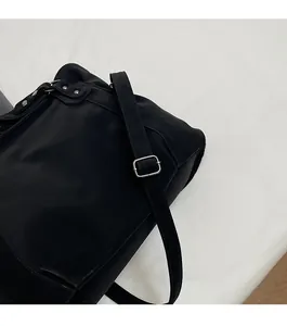 Détail de la bandoulière réglable en toile et boucle en métal argenté sur un sac fourre-tout
