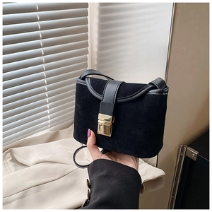 Detail showing matte suede texture and gold metal buckle of the black crossbody bag