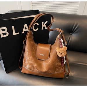 Detail of a brown large capacity leather tote bag with a cute bear plush keychain