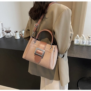 Detail of canvas bucket bag with brown leather trim and silver buckle in a cafe setting