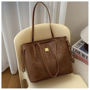 Detail of a brown leather tote bag with vintage texture and gold square buckle detail