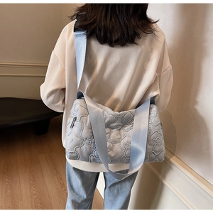 Close-up of light blue quilted crossbody bag with cloud texture and wide fabric strap