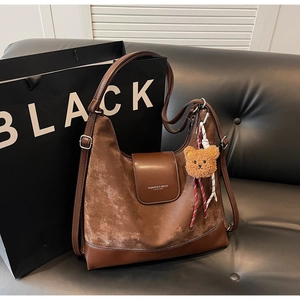 Close-up of retro brown tote bag featuring suede textures and a cute plush bear charm