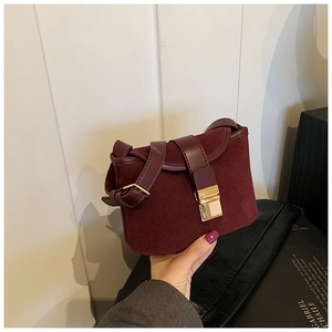 Detail of burgundy frosted suede crossbody bag with vintage gold square metal clasp
