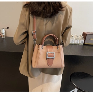 Detail of pink woven bucket bag with metal buckle and adjustable shoulder strap