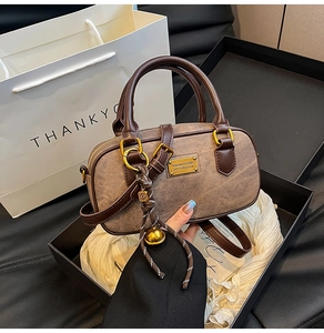Detail view of a brown vintage Boston bag with gold hardware and a woven knot charm