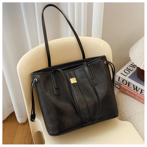 Close-up of black matte tote bag with square gold metal hardware and side drawstring details
