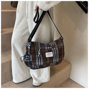 Detail of checkered shoulder bag with side drawstring pocket and black wide strap