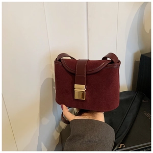 Detail of vintage burgundy matte crossbody bag with gold buckle and leather strap texture