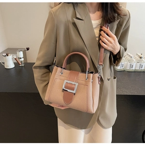 Detail of the light brown textured fabric bucket bag with leather handle and metal buckle